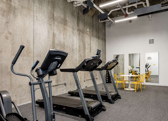 A gym with treadmills and a dining table.