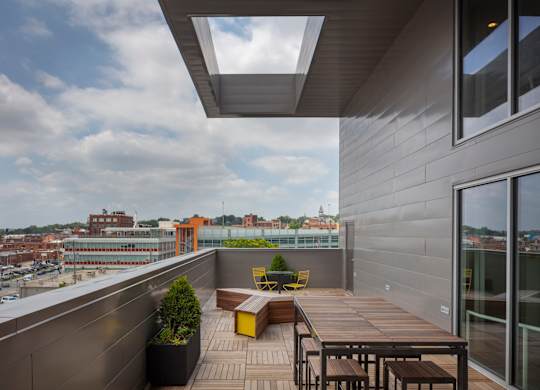 A balcony with a table and chairs overlooking a cityscape.