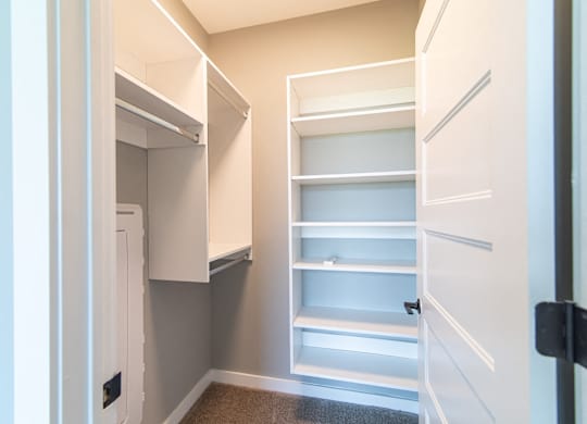A white pantry with open shelves and a white door.