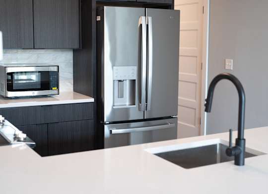 A modern kitchen with a stainless steel refrigerator and a white countertop.