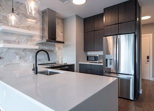 A modern kitchen with a marble backsplash and stainless steel appliances.