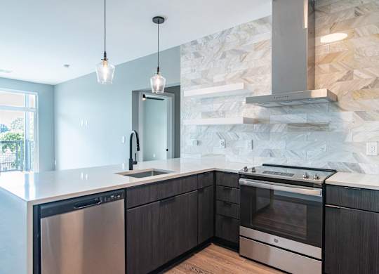 A modern kitchen with a stone backsplash and stainless steel appliances.