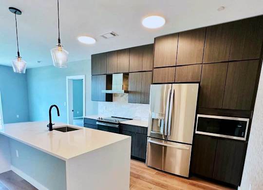 A modern kitchen with a white island and wooden floors.