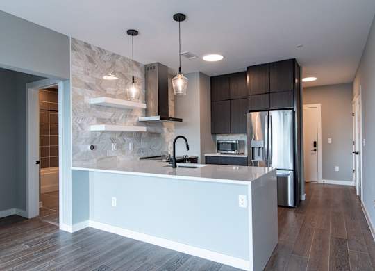 A modern kitchen with a marble backsplash and dark wood cabinets.