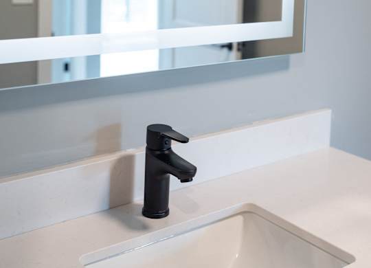 A black faucet is mounted on a white sink.