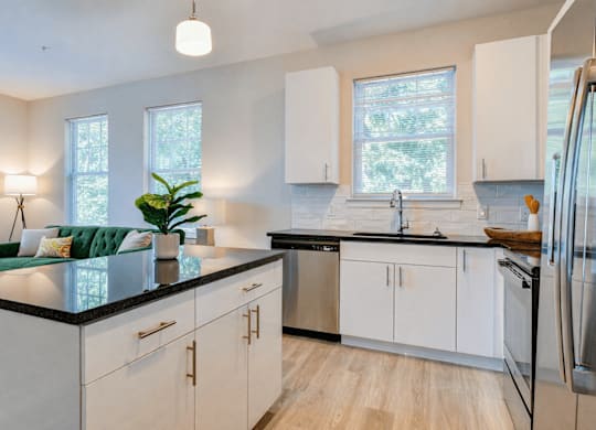 A modern kitchen with white cabinets and a black countertop.