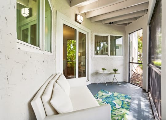 a porch with a white couch and a table on a rug at The Villages of Banyan Grove, Boynton Beach