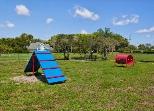 a playground with a blue slide and a red barrel at The Villages of Banyan Grove, Boynton Beach