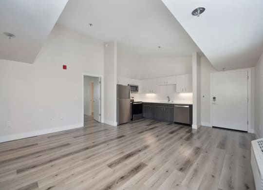 the living room and kitchen of an apartment with wood floors and white walls  at Track 281 Apartments, Sacramento, CA