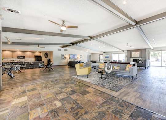 Clubhouse Sitting Area with Hardwood Inspired Floor, Gray Sofa, Rug and Ceiling Fan/Light at The Renaissance Apartments, Citrus Heights, CA 95610