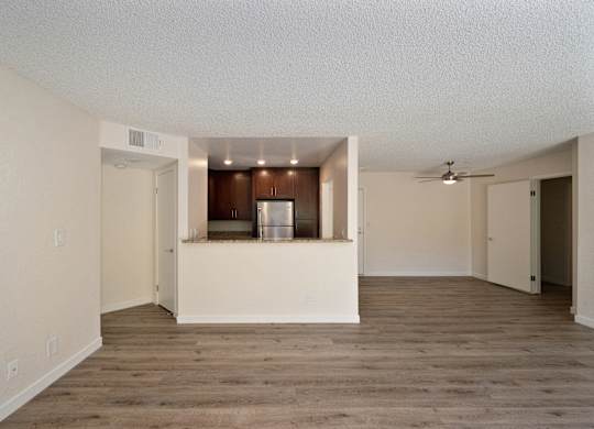 an empty living room with a kitchen in the background at Croft Plaza Apartments, West Hollywood California