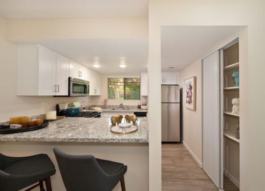a view of a kitchen and a living room with a stainless steel refrigerator and microwave