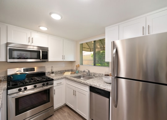 an updated kitchen with stainless steel appliances and white cabinets
