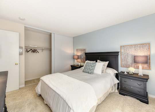 Master bedroom in the model home. Queen size bed with two nightstands. Large closet and carpeting on the floors.at The Renaissance Apartments, Citrus Heights, CA