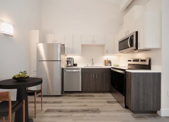 a kitchen with stainless steel appliances and a small table with chairs  at Track 281 Apartments, California, 95811