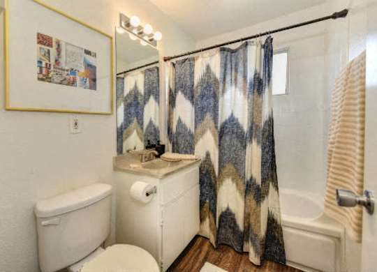Bathroom with Toilet, Decorated Blue/White Shower Curtains and Bathtub at Olympus Park Apartments, Roseville, 95661
