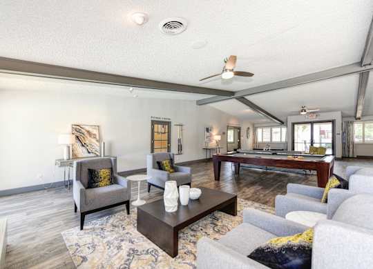 Clubhouse Sitting Area with Couches, White Tables and Pool Table in Distance at The Renaissance Apartments, California