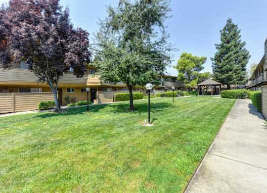 Green Outdoors Walkways with Grass, Trees and Apartment Exteriors  at Olympus Park Apartments, Roseville, 95661