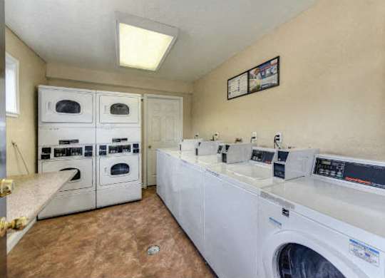 Community Laundry Room with Washers and Dryers, Hardwood Inspired Floors and Ceiling Light at Olympus Park Apartments, Roseville, CA, 95661