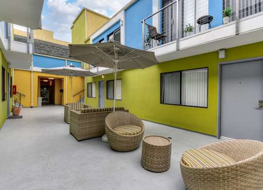 Sitting area in the center of the community. There are wicker chairs, tables and umbrellas for the residents comfort.at Croft Plaza Apartments, West Hollywood, CA 90069