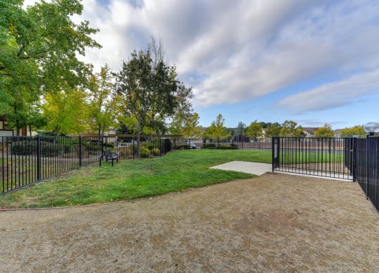 Dog Park with Walking Path, Grass, Trees and Bench in Distance at Rocklin Manor  Apartments, Rocklin  , CA