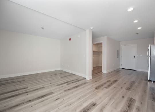 a living room with white walls and wood flooring and a refrigerator  at Track 281 Apartments, Sacramento, 95811
