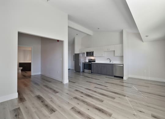 an empty living room with hardwood floors and a kitchen  at Track 281 Apartments, Sacramento