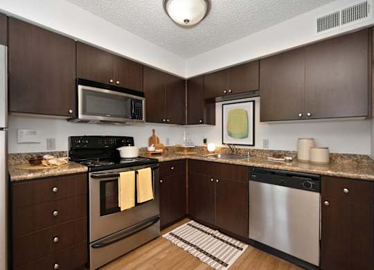 a kitchen with dark wood cabinets and stainless steel appliances at Fountains of Fair Oaks, Fair Oaks, 95628