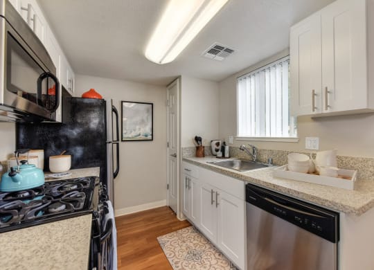Dining Room/Kitchen with Wood Inspired Floor, Rug, Oven, Stove with Blue Tea Kettle, Microwave at Addison Ranch Apartments, Petaluma, CA, 94954