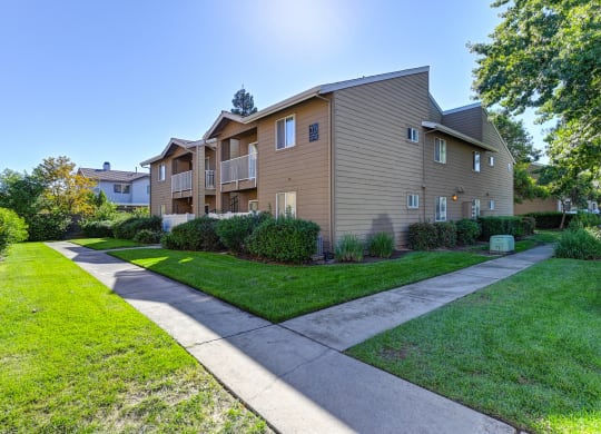 View of a two story apartment building at Hasting Park with a sidewalk and lawn