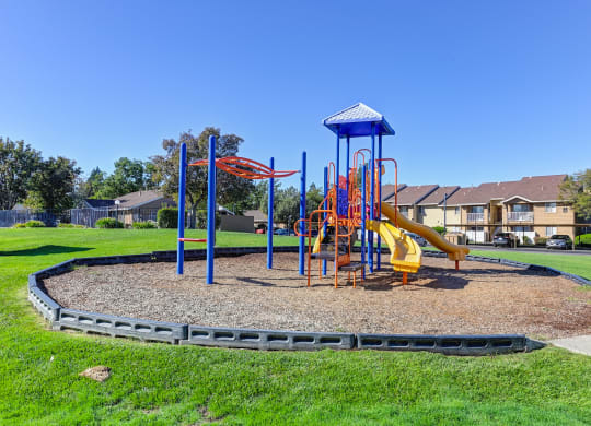 Playground on-site with slides and monkey bars surrounded by large grassy area