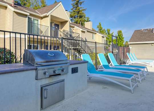 an outdoor patio with chairs and a barbecue grill at Hidden Oaks Apartments, Citrus Heights