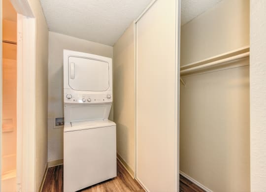 Stackable washer and dryer inside apartment with closet to the right and Hardwood Inspired Floors at Renaissance Park Apartments, Davis