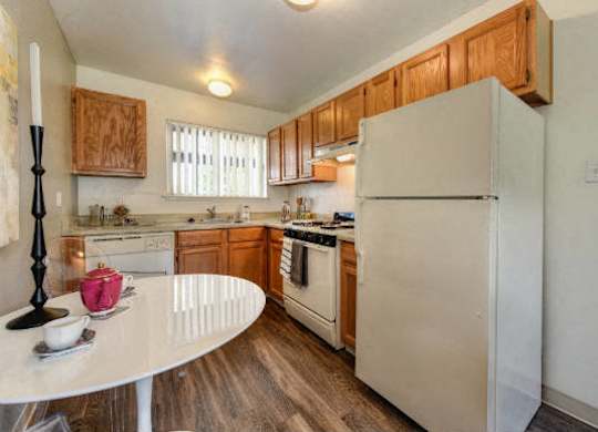 Kitchen with Hardwood Inspired Floors, White Table and Refrigerator at Olympus Park Apartments, Roseville, CA