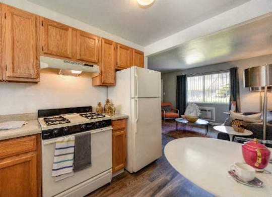 Kitchen with View of Living Room,  Hardwood Inspired Floors, Oven and Wood Cabinets at Olympus Park Apartments, Roseville, 95661