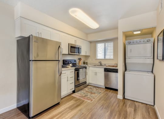 Kitchen with Washer/Dryer , Hardwood Inspired Floor, Refrigerator and White Cabinets at Silverstone Apartments, Davis