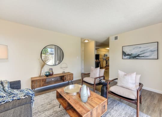 Living room with two tone paint,  Hardwood Inspired Floor, Gray/White Rug, Gray Sofa and Round Mirror at Silverstone Apartments, Davis, CA, 95618