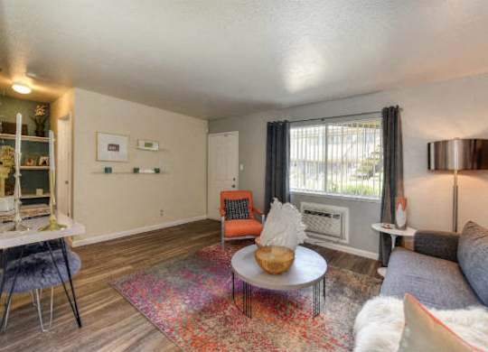 Living Room with Hardwood Inspired Floors, Orange Chairs and Window at Olympus Park Apartments, Roseville, CA