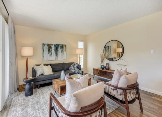 Living room with two tone paint,  Hardwood Inspired Floor, Gray/White Rug, Gray Sofa and Round Mirror  at Silverstone Apartments, Davis, CA