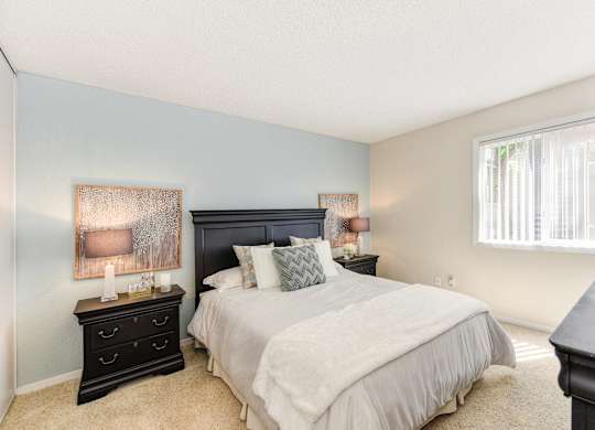 Bedroom with Carpet, Black Headboard, Window and Bedside Dresser at The Renaissance Apartments, California
