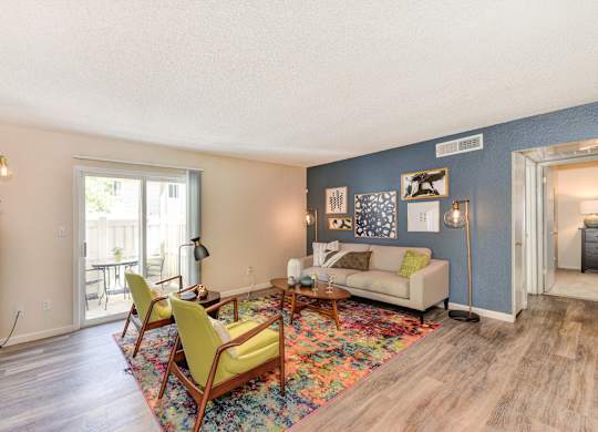 Living Room with Hardwood Inspired Floor, Lime Sofa Chairs, Gray Sofa, Colorful Rug and Sliding Door to Patio at The Renaissance Apartments, Citrus Heights, CA 95610