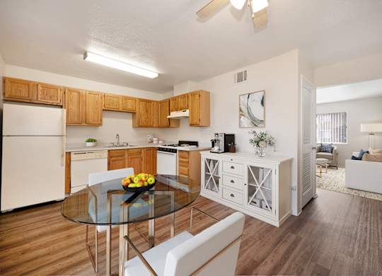 A modern kitchen with wooden cabinets and a glass table.