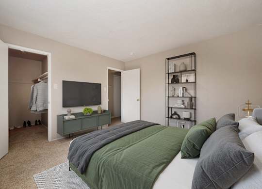 A bedroom with a bed, a television, and a shelf with various items.