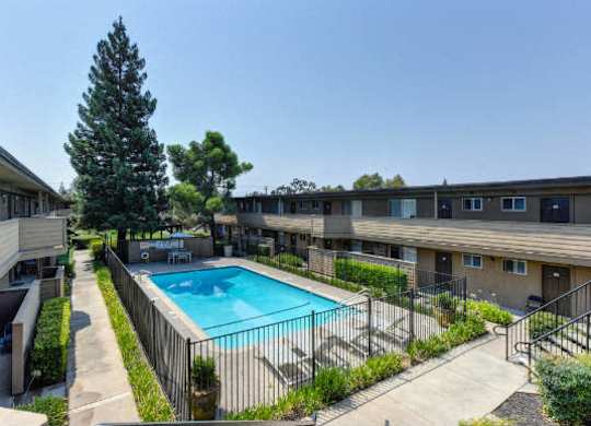 Outdoor Swimming Pool and Lounge Area, Trees, Bushes and Apartment Exteriors  at Olympus Park Apartments, California, 95661