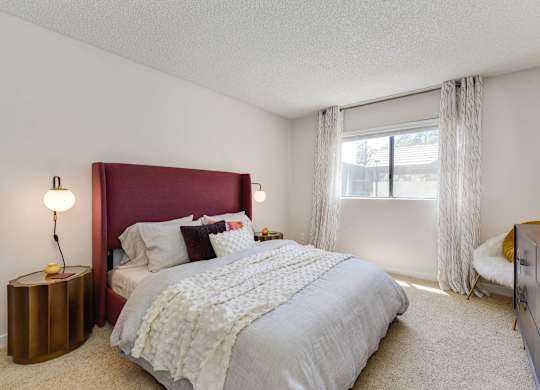 A bedroom with a large bed and a red headboard.