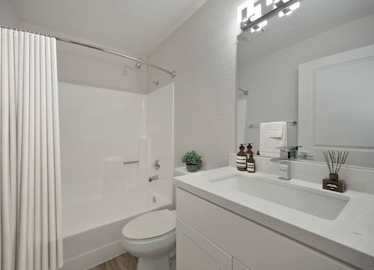 A white bathroom with a toilet, sink, and shower.