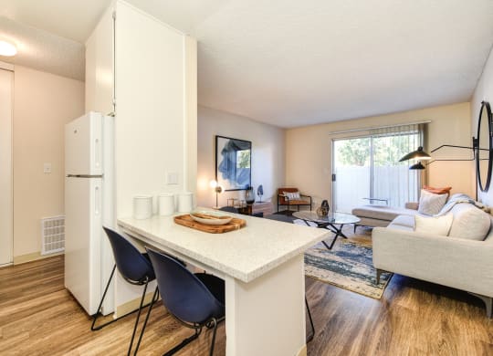 Kitchen with View of Living Room, Hardwood Inspired Floor, White Table and Blue Chairs at Renaissance Park Apartments, California, 95618