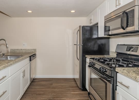 an empty kitchen with white cabinets and stainless steel appliances and a black stove and refrigerator at Rocklin Manor  Apartments, Rocklin  , California