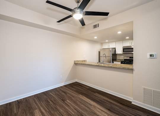 A room with a ceiling fan and wooden flooring.