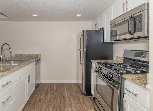 A kitchen with a black refrigerator, stove, and oven.